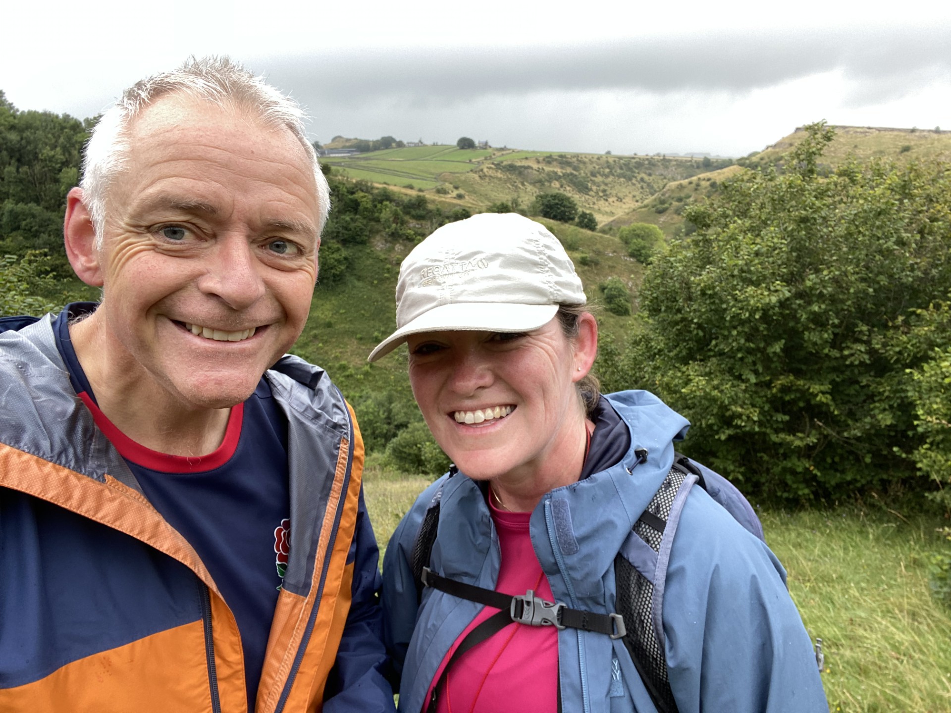 Man and woman smiling for the camera with a countryside background behind them