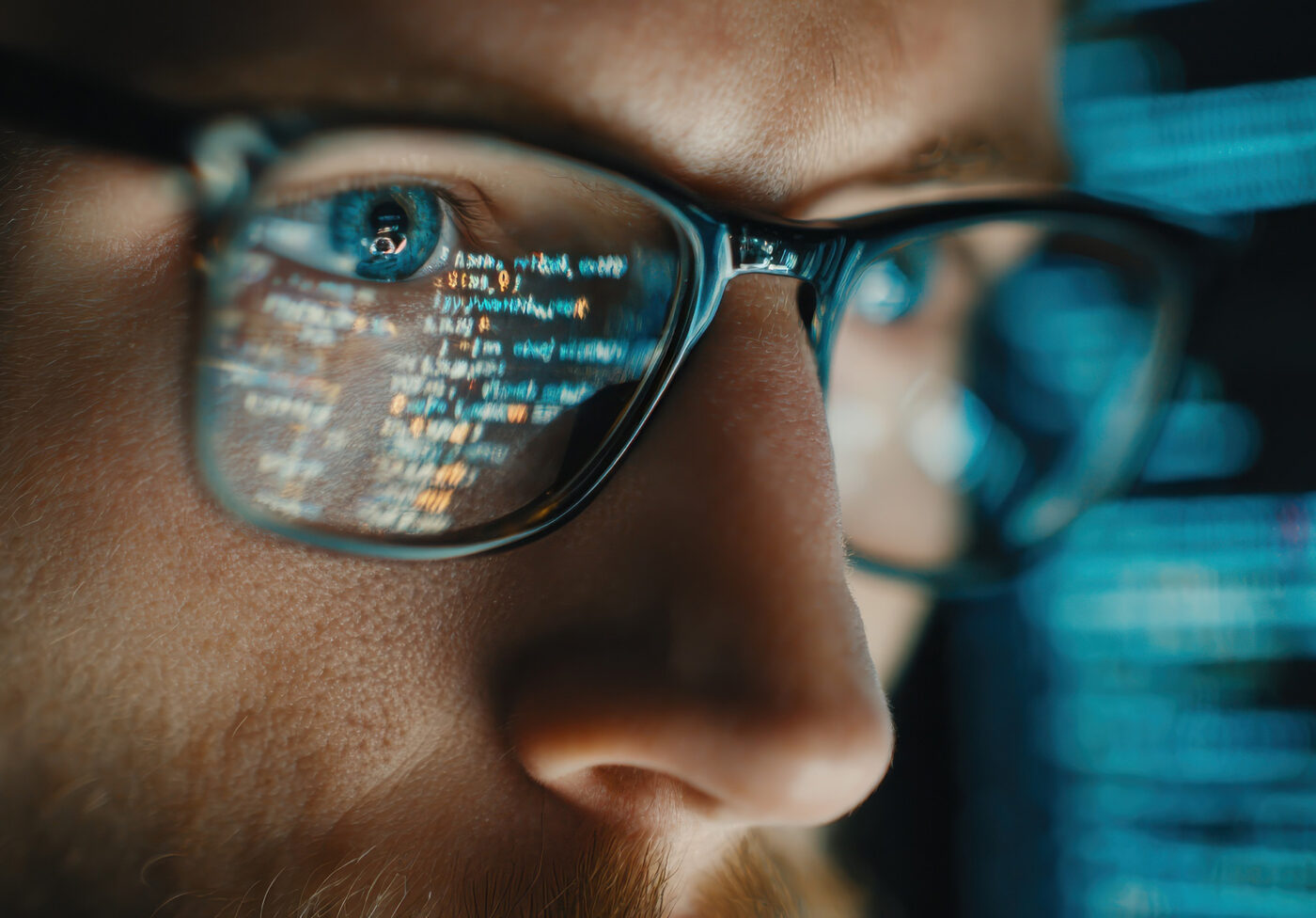 Focused developer coder wears glasses working on computer looking at programming code data cyber security digital tech